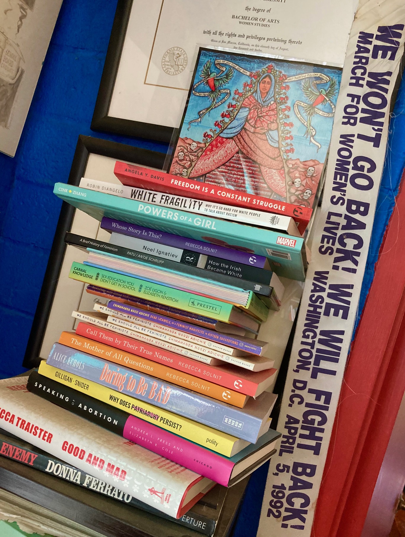 Stack of feminist books with sash from 1992 reproductive rights march on D.C.