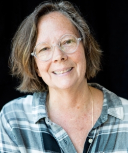 Headshot of K-B, wearing a black-and-white plaid shirt