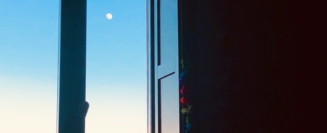 A 3/4 moon seen through a window frame