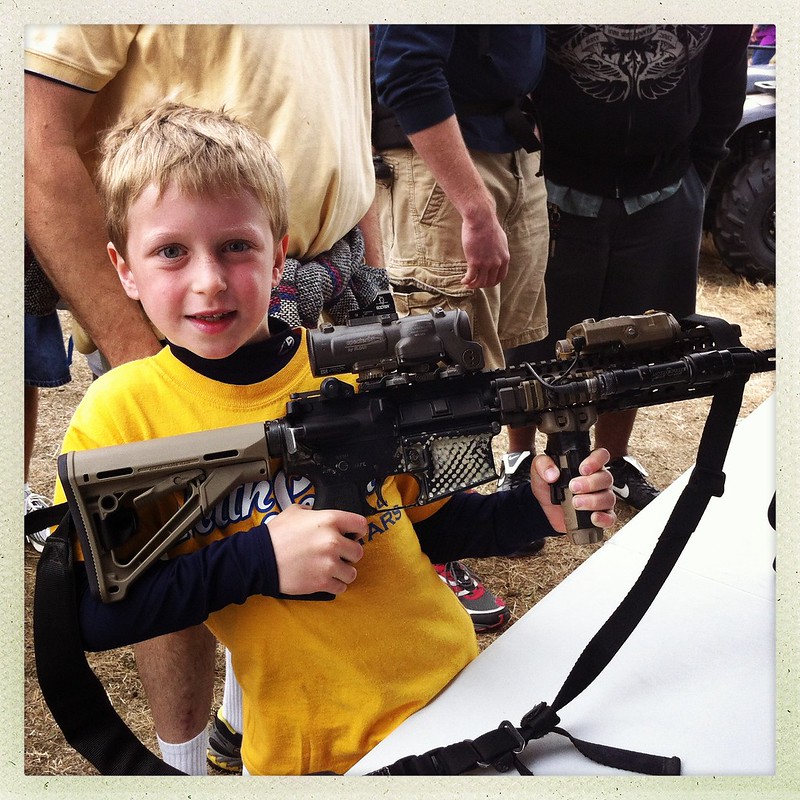 Young, smiling child holding an AR-15.