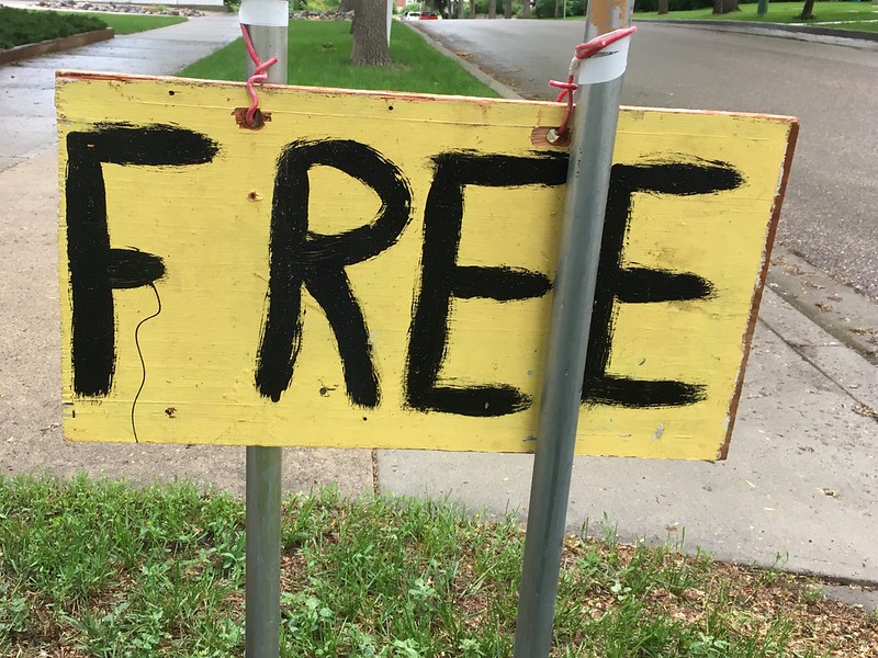 Yellow and black sign tied to two posts and reading "FREE."